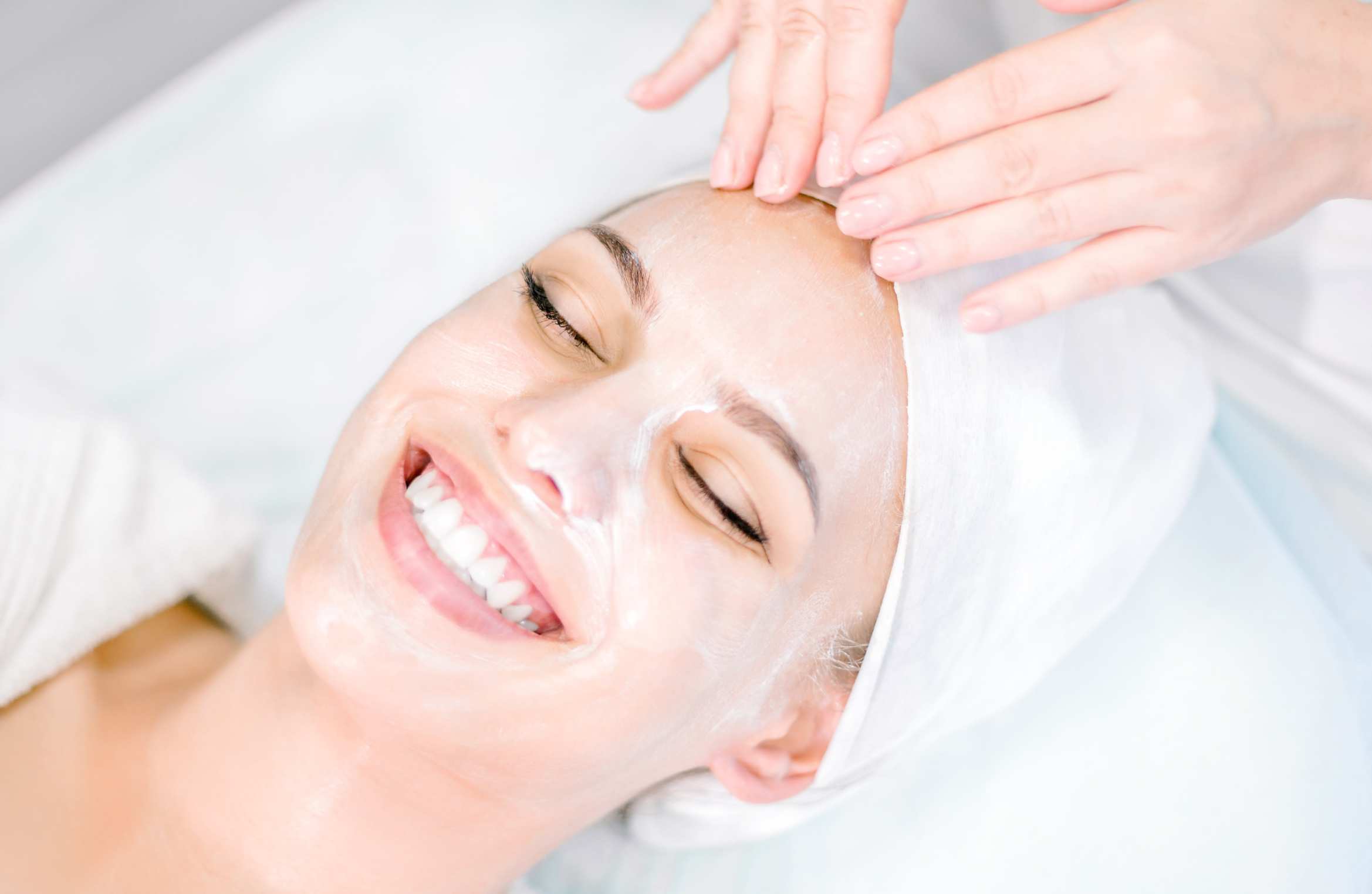 Smiling woman receiving facial spa treatment